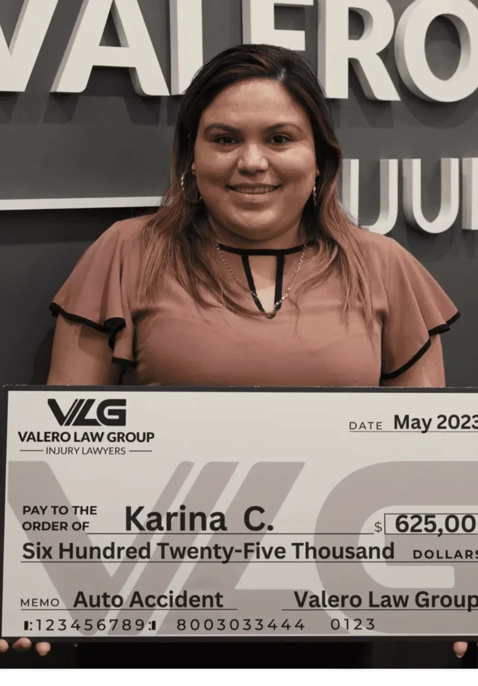 Cliente de Valero Law Group Karina C. sosteniendo un cheque de acuerdo de $625,000 por accidente de auto