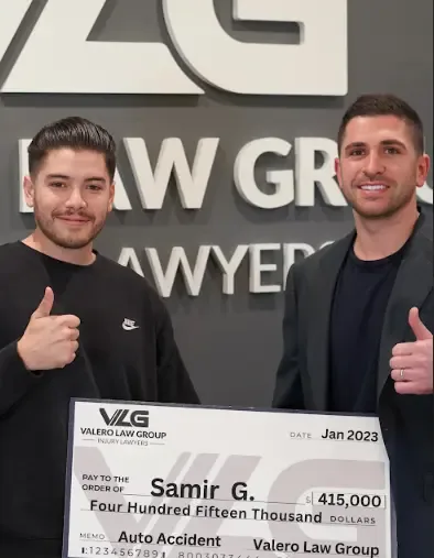 Cliente de Valero Law Group Samir G. sosteniendo un cheque de acuerdo de $415,000 por accidente de auto