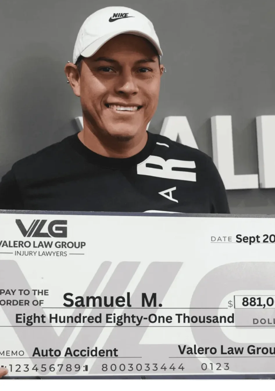 Cliente de Valero Law Group Samuel M. sosteniendo un cheque de acuerdo de $881,000 por accidente de auto
